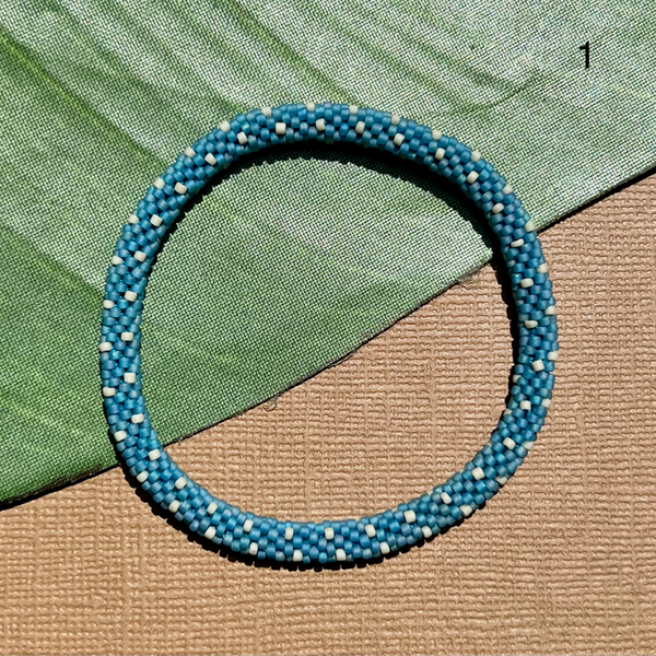 Light blue glass beads are crocheted into a beaded bangle bracelet. Stackable bracelets look great alone with styled with your favorite jewelry.